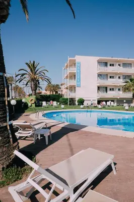 a swimming pool with lounge chairs and a building at Hotel Subur Maritim in Sitges