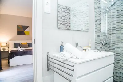 a bathroom with a sink and a shower and a bedroom at BarcelonaForRent Urban Town Suites in Barcelona