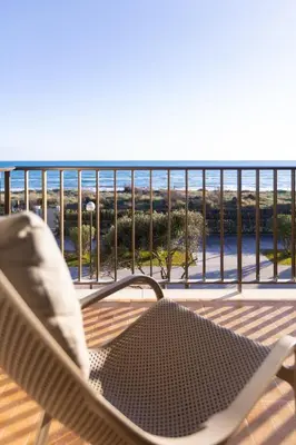 a chair on a deck with a view of the ocean at LETS HOLIDAYS Beach front apartment in Gavà Mar, Pine Beach in Gavà