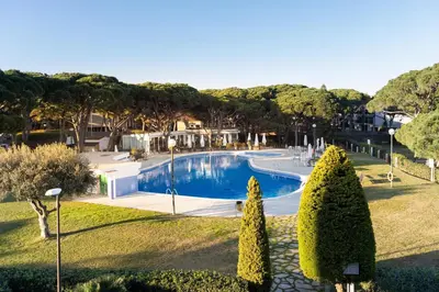 a swimming pool in a yard with trees and houses at LETS HOLIDAYS Beach front apartment in Gavà Mar, Pine Beach in Gavà