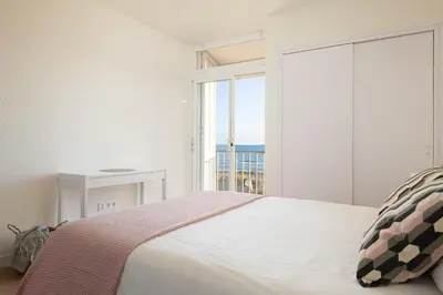 a bedroom with a bed and a large window at LETS HOLIDAYS Beach front apartment in Gavà Mar, Pine Beach in Gavà