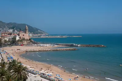 a beach with a bunch of people and the ocean at Calipolis in Sitges