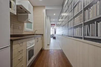 a kitchen with white cabinets and a long hallway at Alcam Books in Barcelona