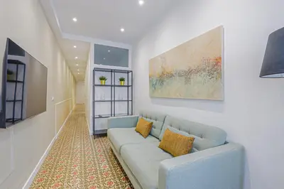 a living room with a blue couch and a painting at Alcam Books in Barcelona