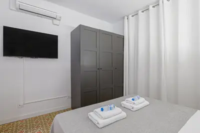 a bedroom with two towels on a bed with a television at Alcam Books in Barcelona
