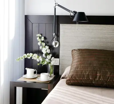 a bed with a table with a vase of flowers on it at Park Hotel in Barcelona