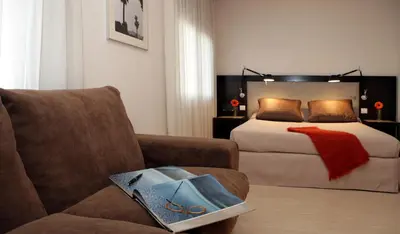a bedroom with a bed and a couch and a chair at Park Hotel in Barcelona
