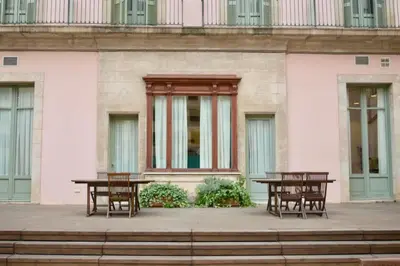 two tables and chairs in front of a pink building at Onix Rambla in Barcelona