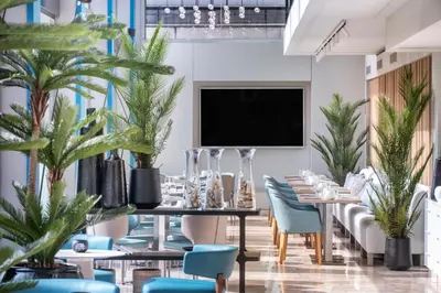 a dining room with a table and chairs and plants at Salles Ciutat del Prat Barcelona Airport in El Prat de Llobregat
