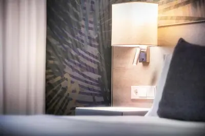 a room with a bed with a lamp and a chair at Salles Ciutat del Prat Barcelona Airport in El Prat de Llobregat
