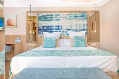 a bedroom with a large bed with blue and white pillows at Sumus Hotel Stella and Spa 4S Adults Recommended in Pineda de Mar