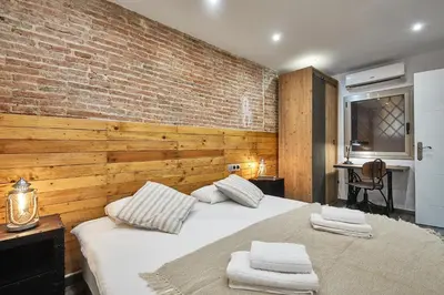 a bedroom with a large white bed with a brick wall at BBarcelona Dúplex Poble Sec in Barcelona