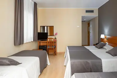 a hotel room with two beds and a desk at Catalunya in Barcelona