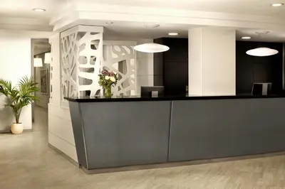 an office lobby with a reception counter with flowers at NH Barcelona Stadium in Barcelona