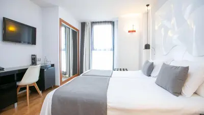 a bedroom with a bed and a desk and a television at Evenia Rocafort in Barcelona