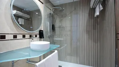 a bathroom with a sink and a shower with a mirror at Evenia Rocafort in Barcelona