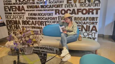 a woman sitting on a chair reading a book at Evenia Rocafort in Barcelona