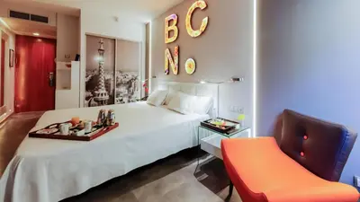 a hotel room with a bed and a desk with a chair at Evenia Rossello in Barcelona