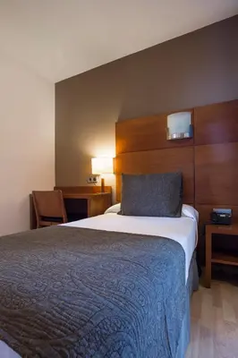 a hotel room with a bed with a blue blanket at Hotel Via Augusta in Barcelona
