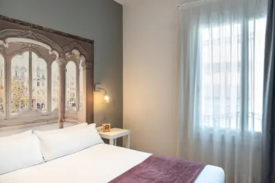 a bedroom with a bed and a large window at Mesón Castilla Atiram Hotels in Barcelona