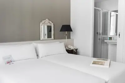 a bedroom with a white bed and a mirror at Mesón Castilla Atiram Hotels in Barcelona