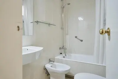 a bathroom with a toilet and a tub and a sink at Mesón Castilla Atiram Hotels in Barcelona