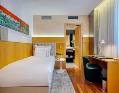 a hotel room with a white bed and a desk and a desk at Sansi Pedralbes in Barcelona