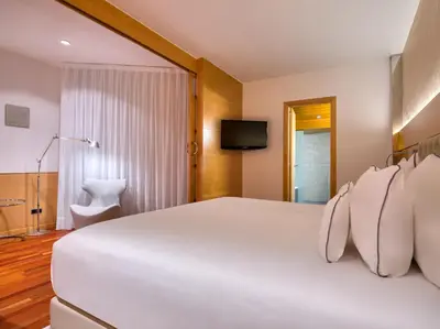 a bedroom with a large white bed and a television at Sansi Pedralbes in Barcelona