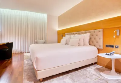 a bedroom with a large white bed and a table at Sansi Pedralbes in Barcelona