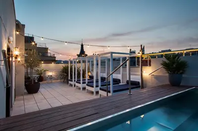 a rooftop deck with a swimming pool at night at Hotel Midmost by Majestic Hotel Group in Barcelona