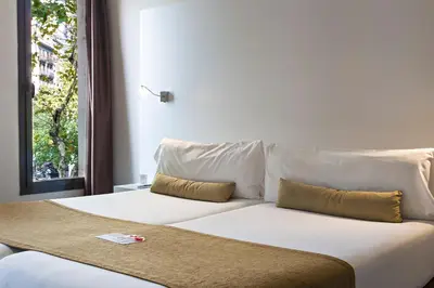 a white bed with two pillows and a window at BCN Urbaness Hotels Del Comte in Barcelona