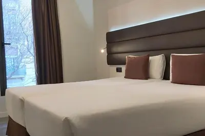 a large white bed in a hotel room with a window at BCN Urbaness Hotels Del Comte in Barcelona