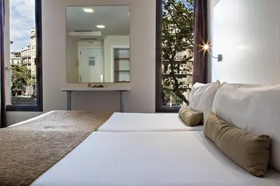 a bedroom with a large bed with a large window at BCN Urbaness Hotels Del Comte in Barcelona