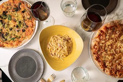 a table with plates of pasta and glasses of wine at Catalonia Barcelona Beach in Barcelona