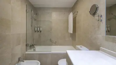 a bathroom with a tub and a toilet and a sink at AC Hotel Victoria Suites by Marriott in Barcelona