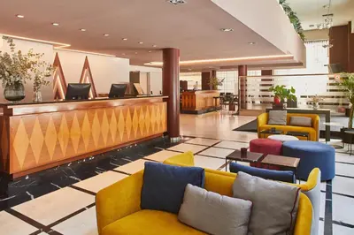 a lobby with yellow and blue chairs and a bar at Silken Sant Gervasi in Barcelona