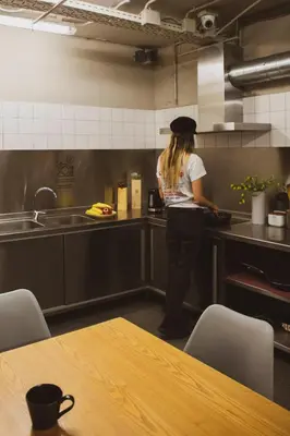 a woman standing in a kitchen preparing food at TOC Hostel Barcelona in Barcelona