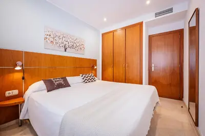 a bedroom with a large white bed and wooden cabinets at Apartaments Marina - Abapart in Barcelona