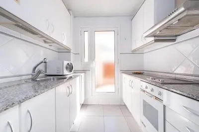 a white kitchen with a sink and a microwave at Aparthotel Napols - Abapart in Barcelona