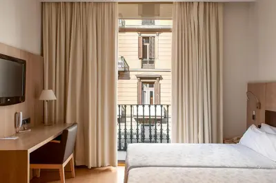 a hotel room with a bed and a desk and a window at Hotel Lleó in Barcelona