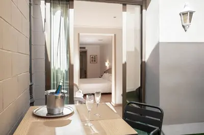 a table with two wine glasses and a room with a bed at Hotel Lleó in Barcelona