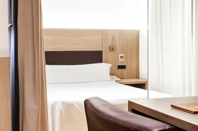 a hotel room with a bed and a desk and a mirror at Hotel Lleó in Barcelona