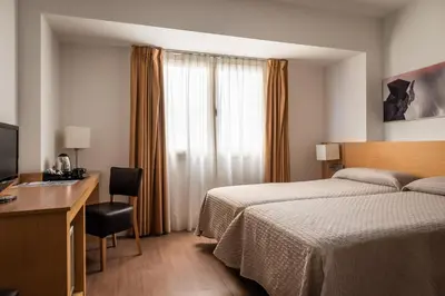 a hotel room with a bed and a desk and a television at Hotel Sagrada Familia in Barcelona