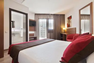a hotel room with a bed and a red chair at Hotel Best Auto Hogar in Barcelona