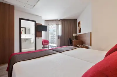 a hotel room with a large bed and a red chair at Hotel Best Auto Hogar in Barcelona