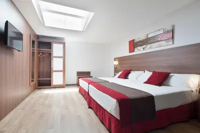 a bedroom with two beds and a flat screen tv at Hotel Best Auto Hogar in Barcelona