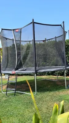 a trampoline with a net on the grass at Cal Colina - Karaktervol landhuis met privé zwembad in Pacs del Penedes