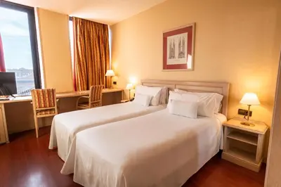 a hotel room with a large white bed and a desk at Sunotel Aston in Barcelona
