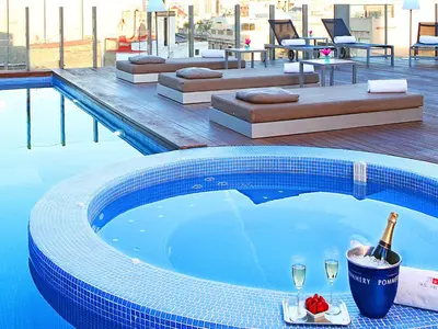 a swimming pool with a bottle of champagne and wine glasses at Axel Hotel Barcelona - Adults Only in Barcelona