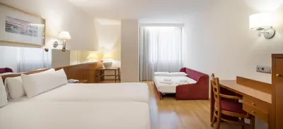 a hotel room with a white bed and a desk at Ilunion Les Corts Spa in Barcelona